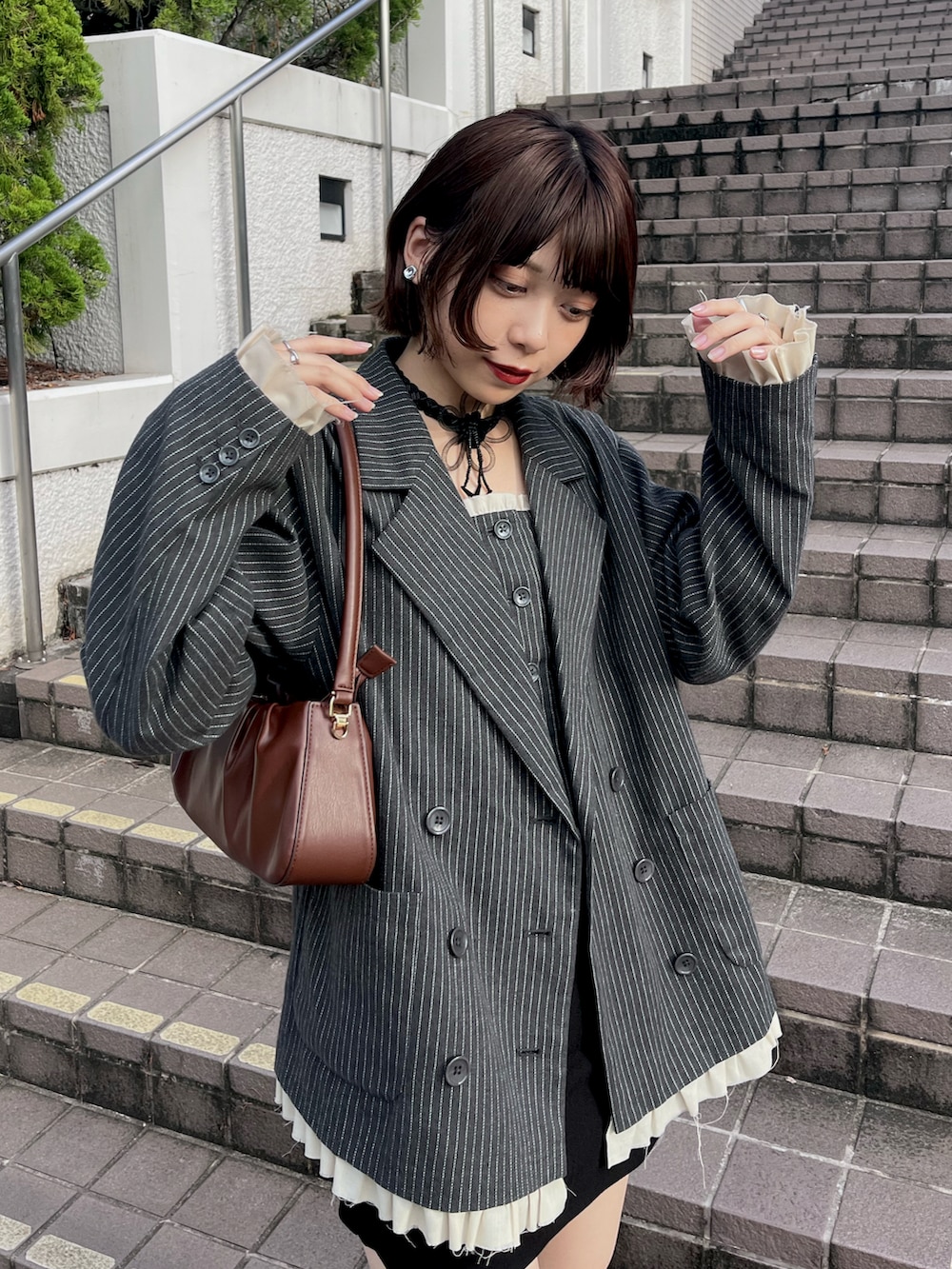 グレー系のテーラードジャケット、ブラック系のスカート、ブラック系のブーツを着用したレディースの夏コーディネートの2枚目の写真