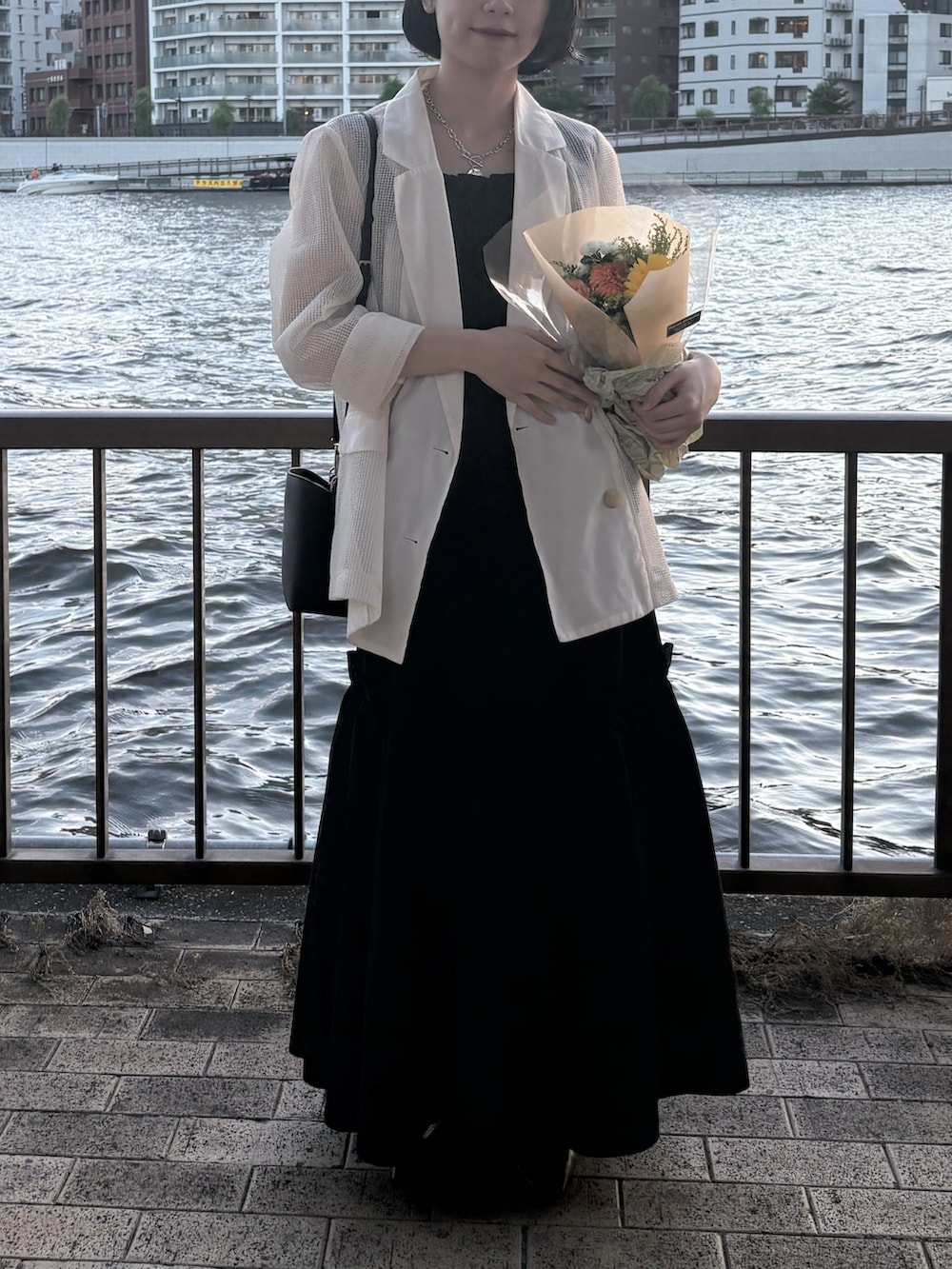 ブラック系のワンピース、ベージュ系のテーラードジャケット、ブラック系のショルダーバッグを着用したレディースの夏コーディネートの3枚目の写真