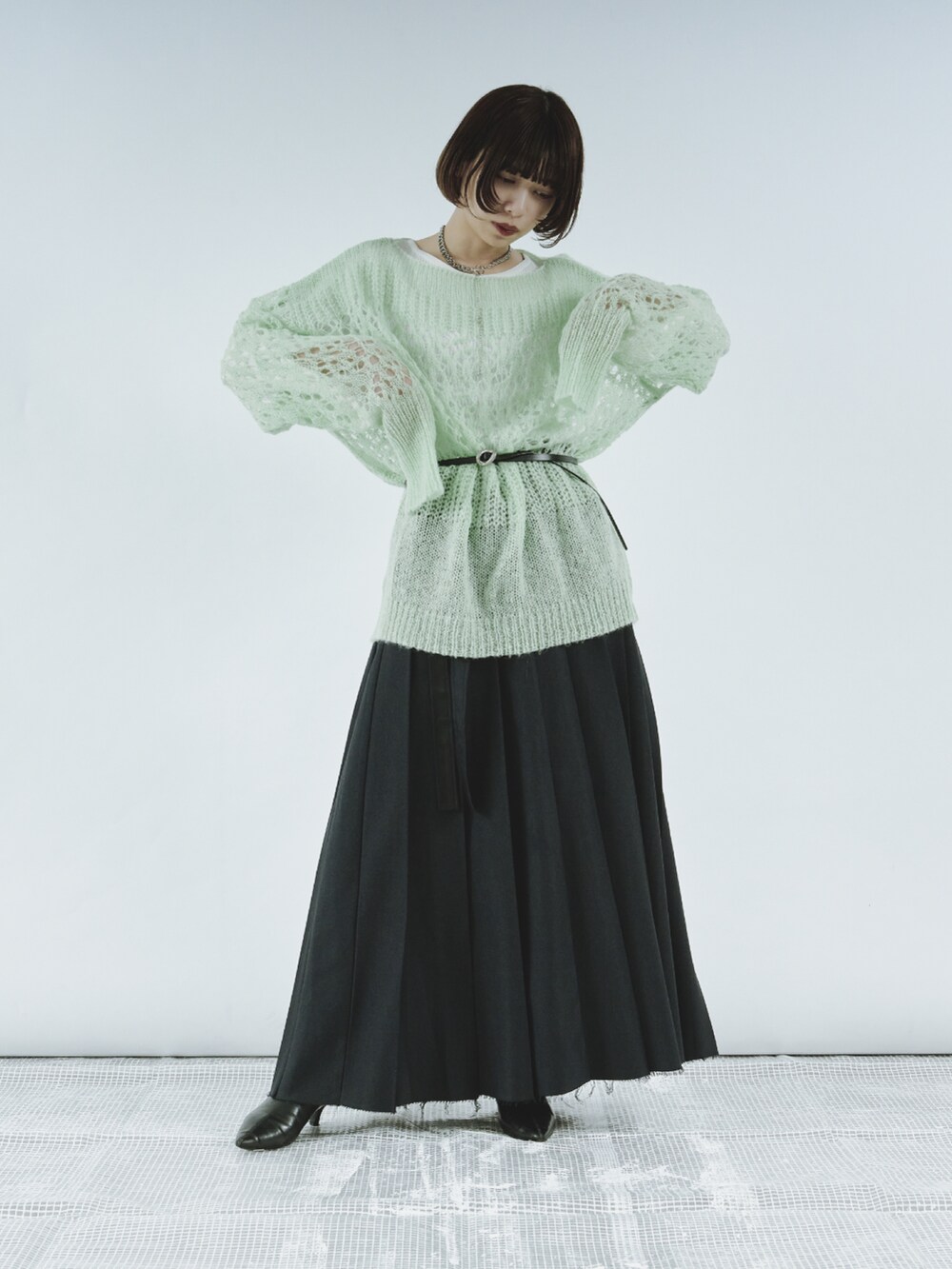 ブルー系のニット/セーター、グレー系のスカート、シルバー系のベルトを着用したレディースの冬コーディネートの2枚目の写真