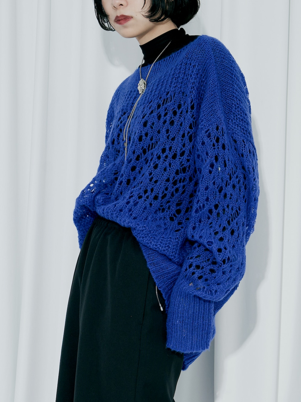 ブルー系のニット/セーター、ブラック系のスラックス、ブラック系のパンプスを着用したレディースの冬コーディネートの5枚目の写真