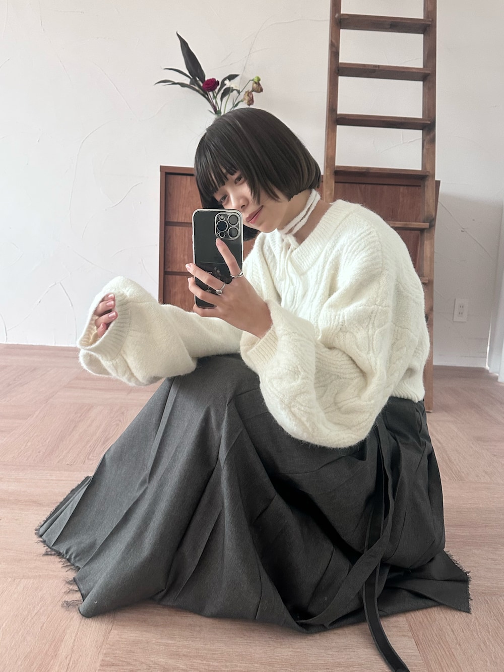 グレー系のスカート、シルバー系のブーツ、ホワイト系のニット/セーターを着用したレディースの冬コーディネートの2枚目の写真