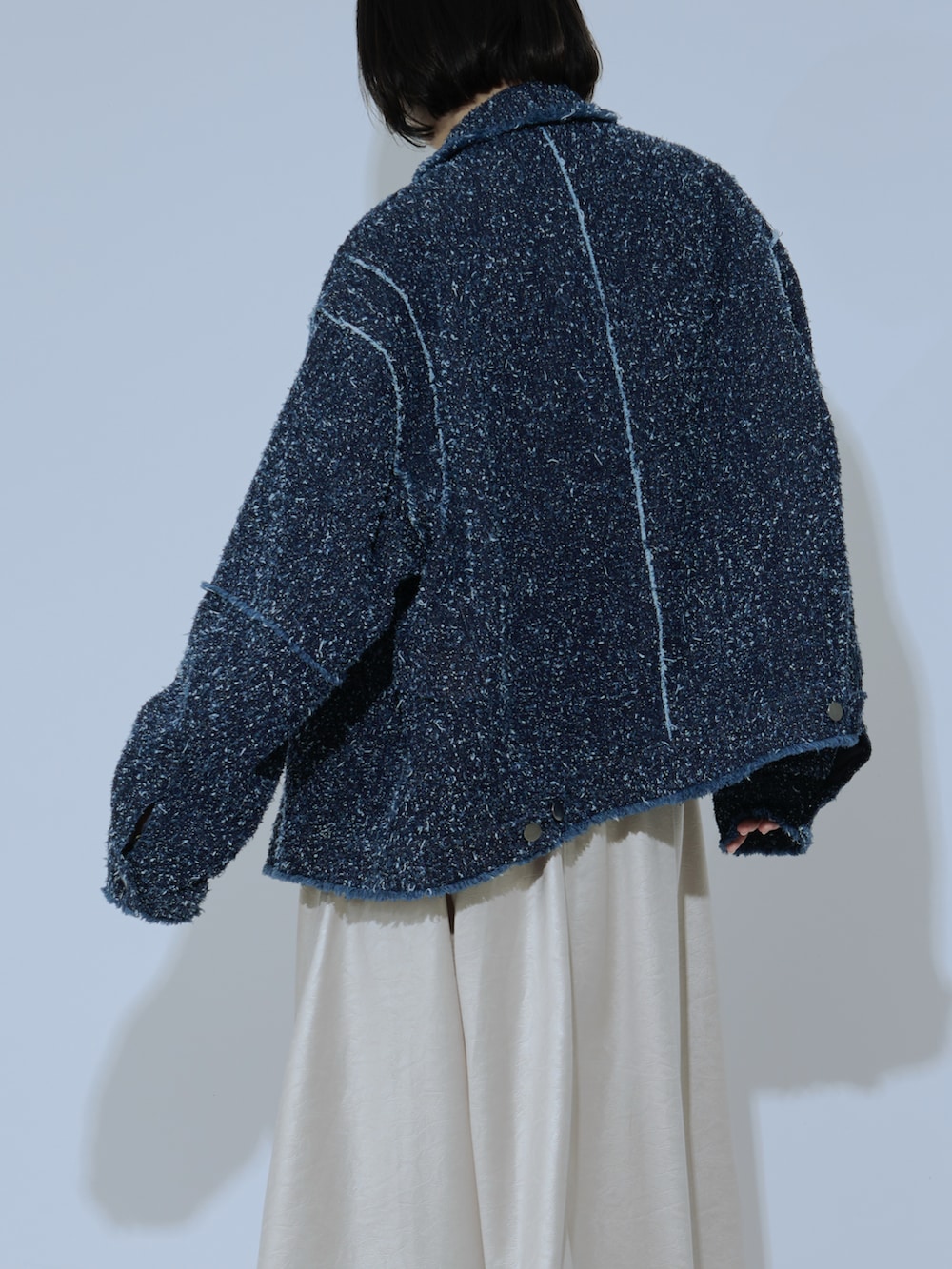 ブラック系のデニムジャケット、ベージュ系のスカート、ブラック系のニット/セーターを着用したレディースの冬コーディネートの3枚目の写真