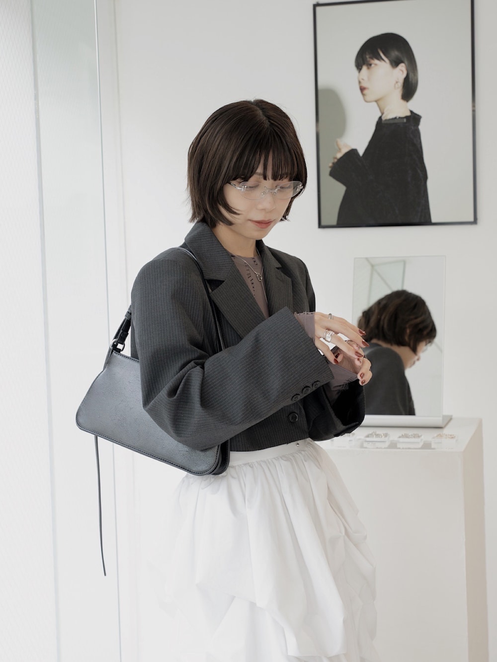 ホワイト系のスカート、ブラック系のジャケット/アウター、グレー系のTシャツ/カットソーを着用したレディースの秋コーディネートの2枚目の写真