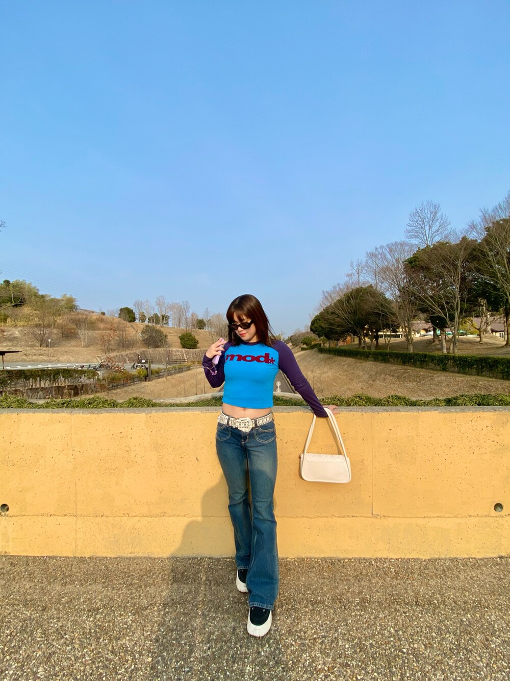 ホワイト系のバッグ、ブルー系のTシャツ/カットソー、ブラック系のスニーカーを着用したレディースの春コーディネートの2枚目の写真