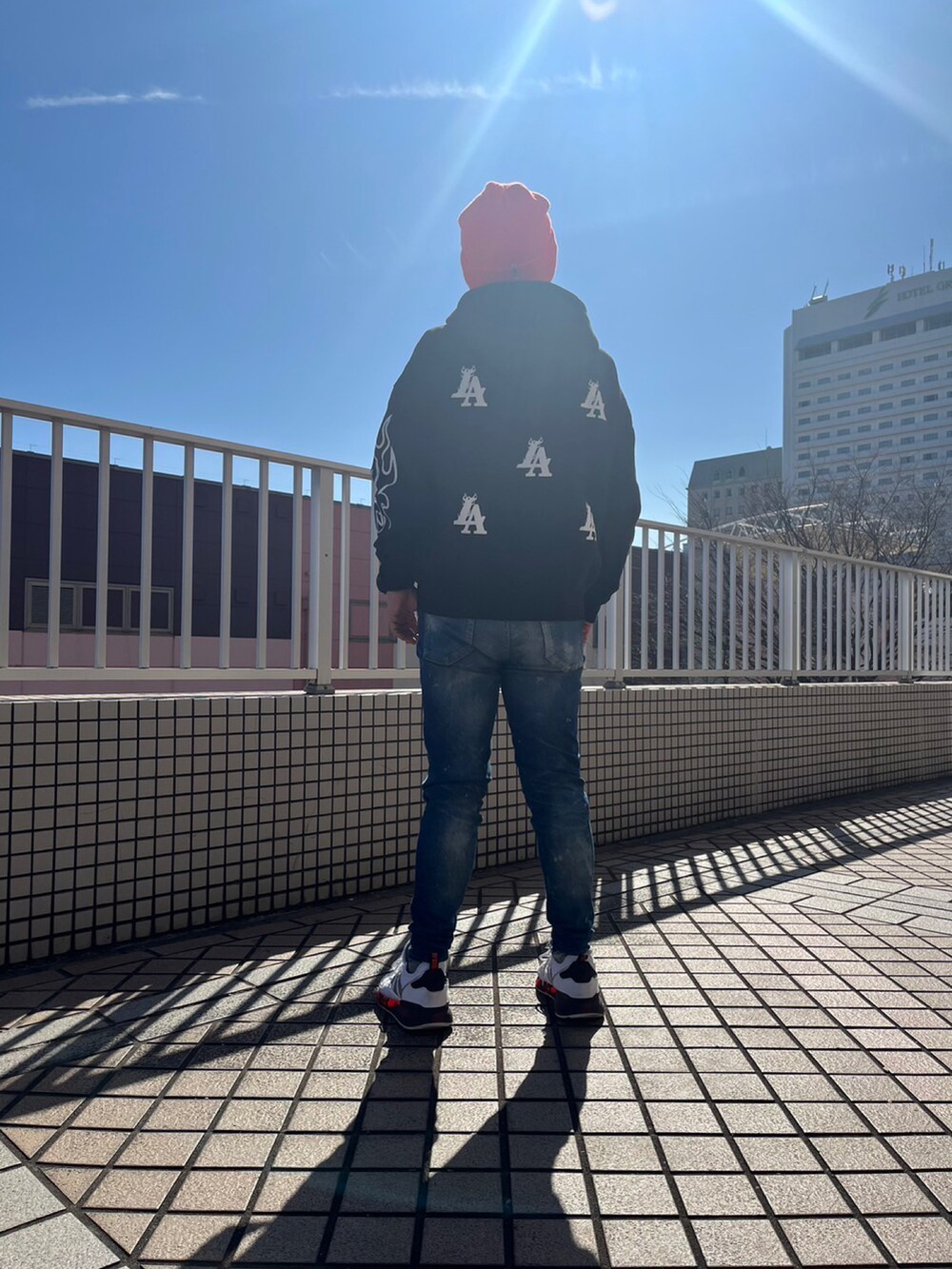 ホワイト系のスニーカー、ブルー系のデニムパンツ、オレンジ系のダウンジャケット/コートを着用したメンズの冬コーディネートの2枚目の写真