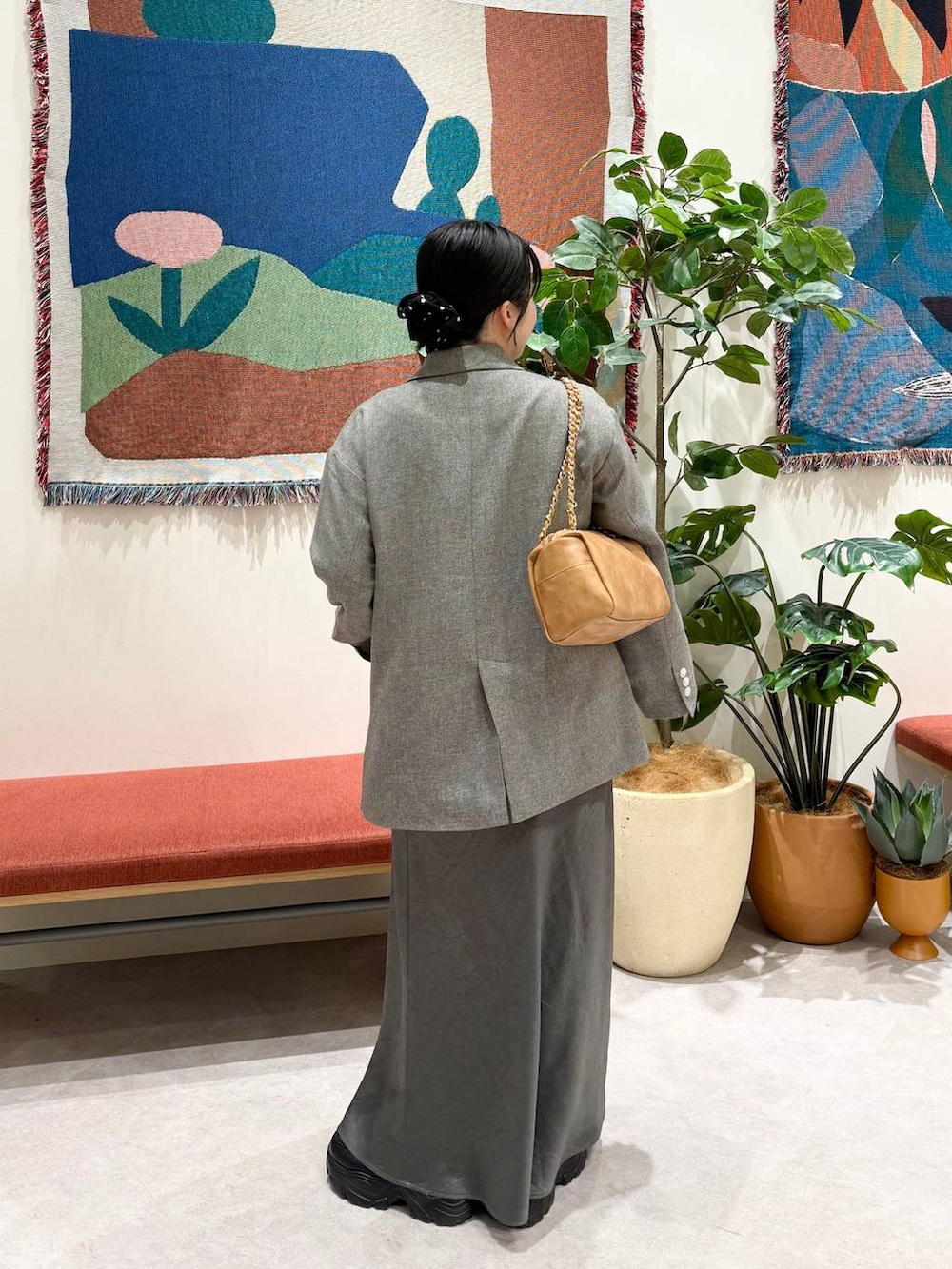 グレー系のスカート、グレー系のテーラードジャケット、ベージュ系のショルダーバッグを着用したレディースの冬コーディネートの2枚目の写真