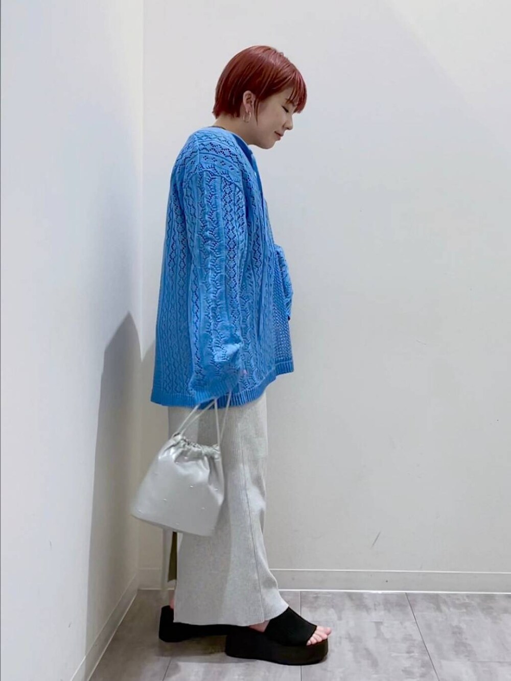 グレー系のスカート、ブルー系のニット/セーター、シルバー系のショルダーバッグを着用したレディースの春コーディネートの4枚目の写真