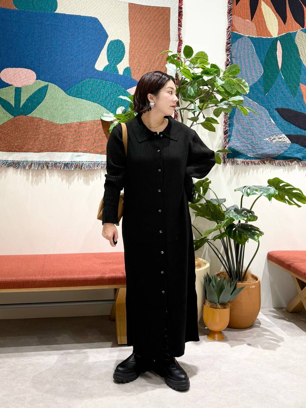 ブラウン系のショルダーバッグ、ブラック系のワンピース、ブラック系のブーツを着用したレディースの秋コーディネートの2枚目の写真