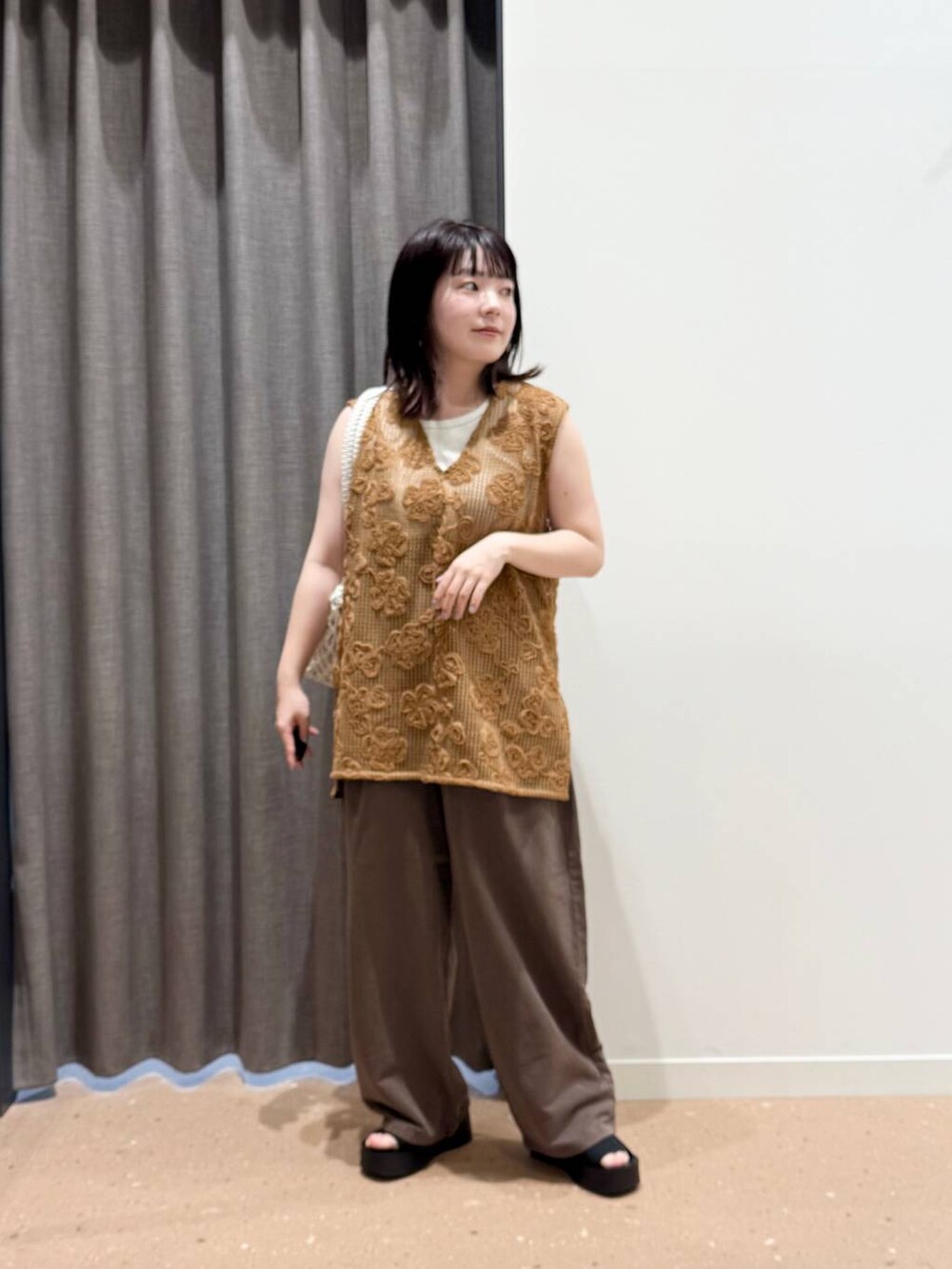 ホワイト系のタンクトップ、ブラック系のサンダル、ホワイト系のトートバッグを着用したレディースの春コーディネートの3枚目の写真