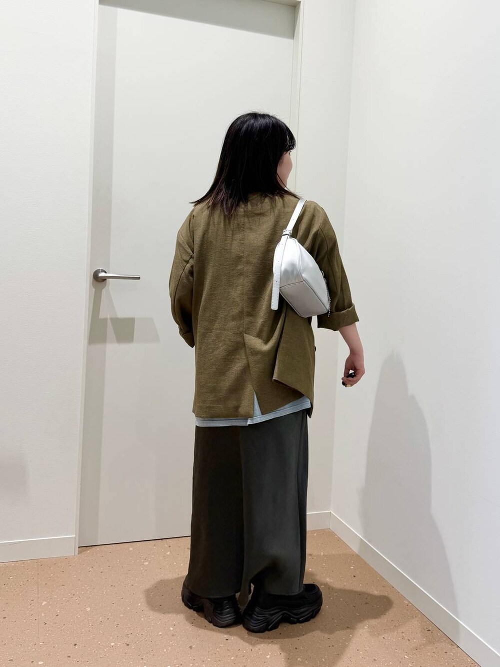 ブラウン系のテーラードジャケット、シルバー系のトートバッグ、ブラック系のスニーカーを着用したレディースの春コーディネートの3枚目の写真