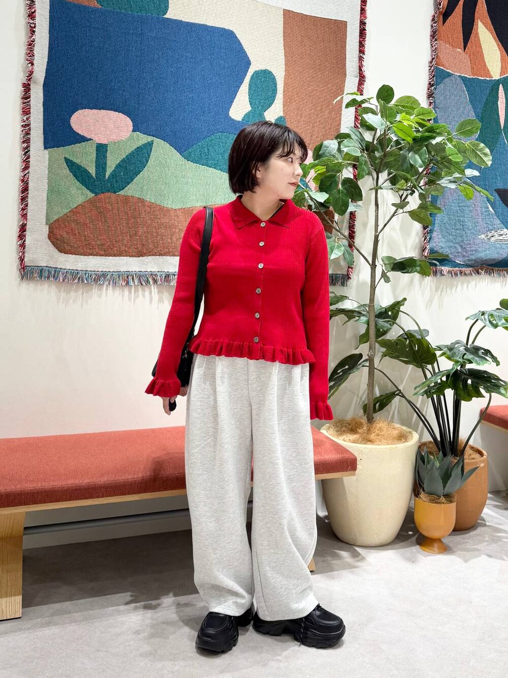グレー系のスウェットパンツ、レッド系のニット/セーター、ブラック系のスニーカーを着用したレディースの秋コーディネートの2枚目の写真