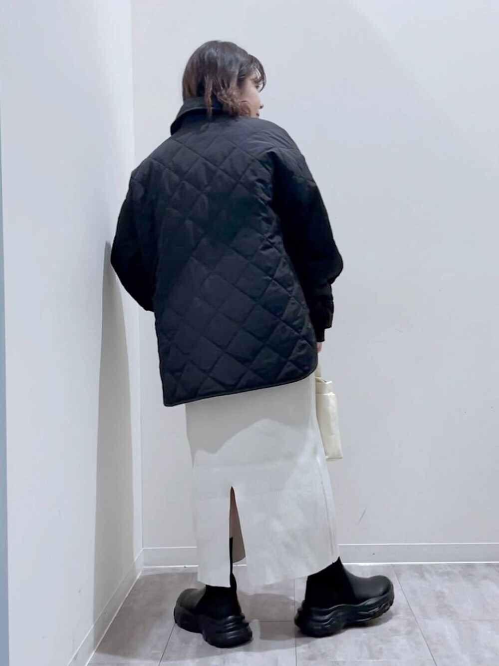 イエロー系のニット/セーター、ホワイト系のショルダーバッグ、ブラック系のブーツを着用したレディースの冬コーディネートの3枚目の写真