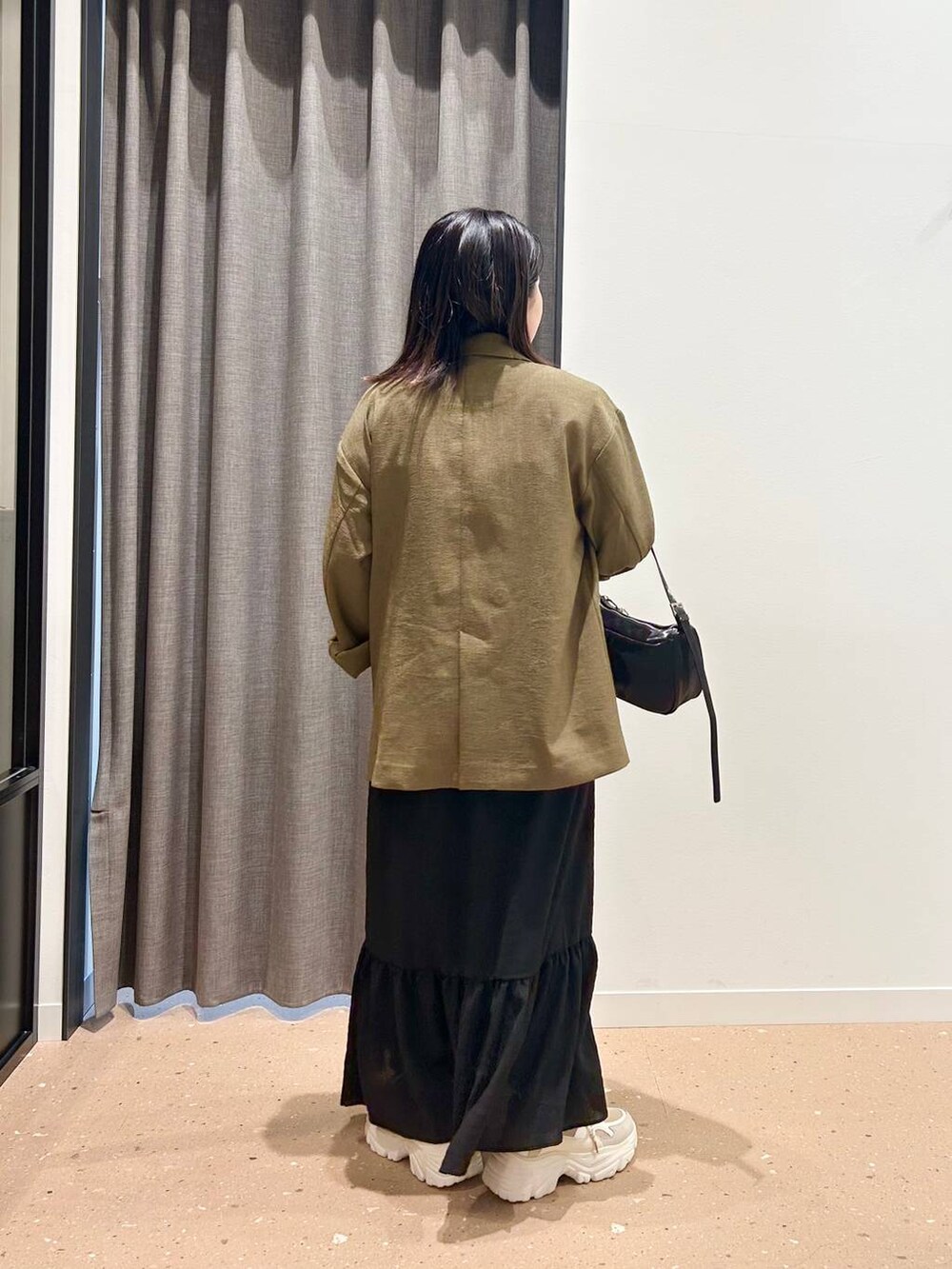 ブラウン系のテーラードジャケット、ブラック系のトートバッグ、ベージュ系のスニーカーを着用したレディースの春コーディネートの4枚目の写真