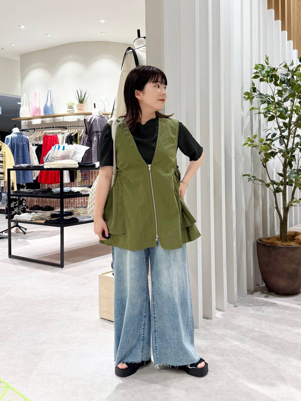 ブラック系のサンダル、ホワイト系のトートバッグ、ブルー系のデニムパンツを着用したレディースの春コーディネートの3枚目の写真