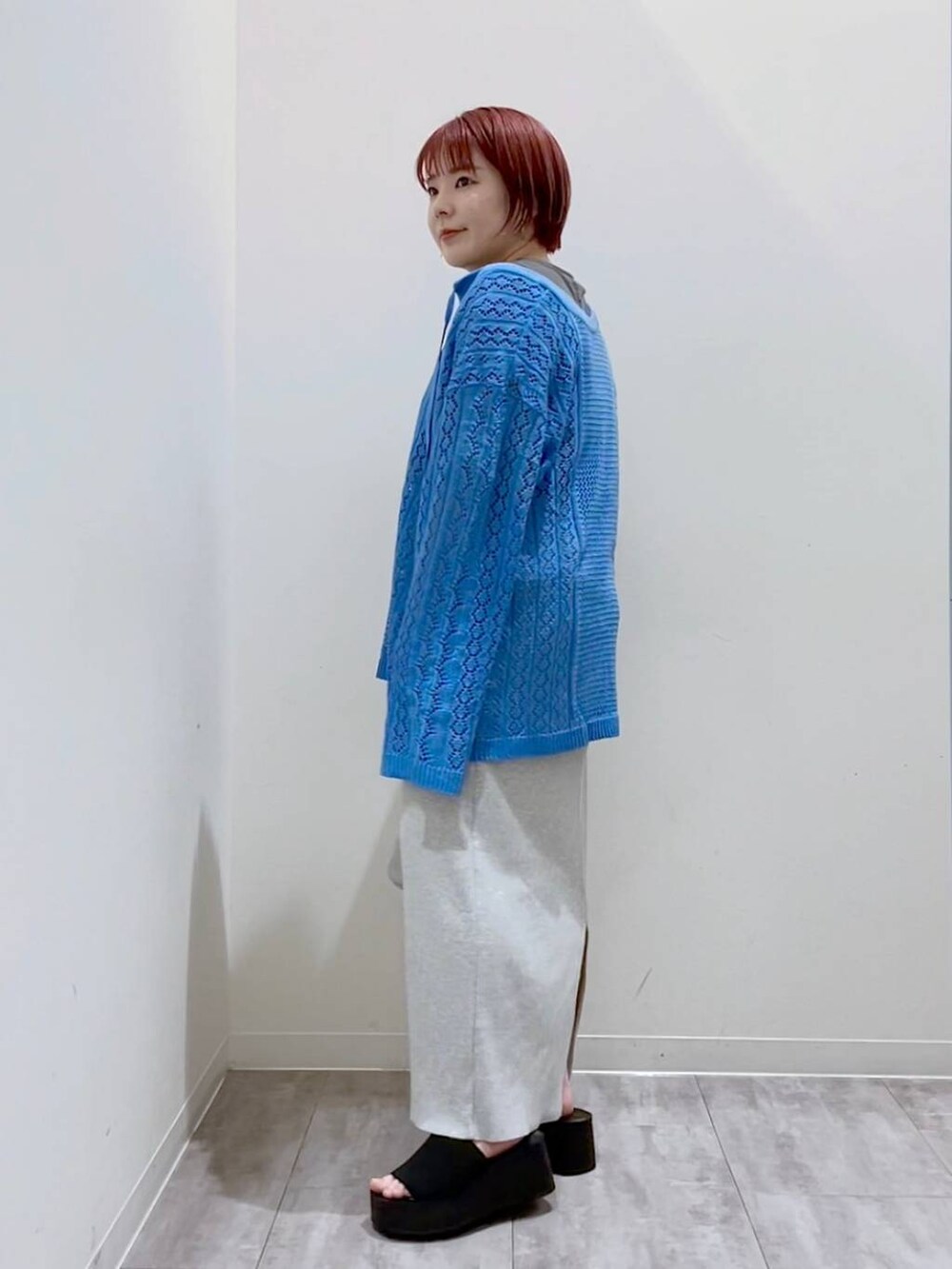 グレー系のスカート、ブルー系のニット/セーター、シルバー系のショルダーバッグを着用したレディースの春コーディネートの2枚目の写真