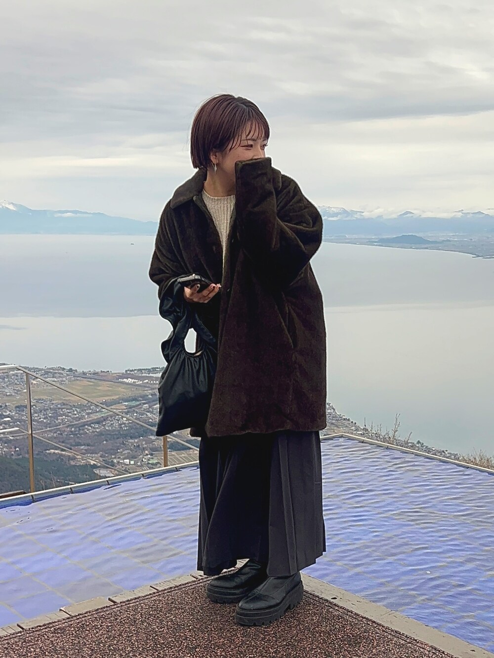 ブラック系のブーツ、グリーン系のその他アウター、ホワイト系のトップスを着用したレディースの冬コーディネートの2枚目の写真