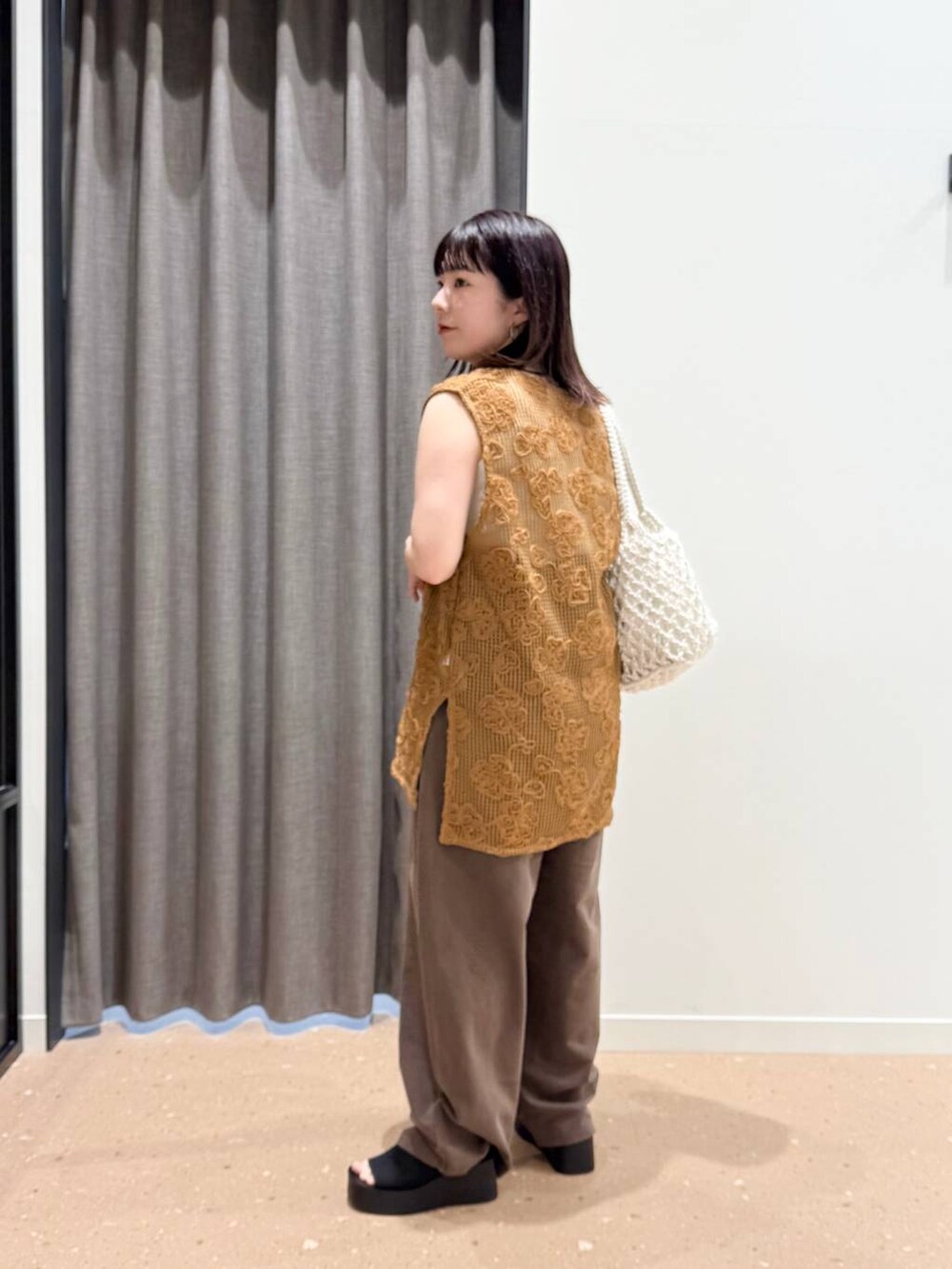 ホワイト系のタンクトップ、ブラック系のサンダル、ホワイト系のトートバッグを着用したレディースの春コーディネートの2枚目の写真