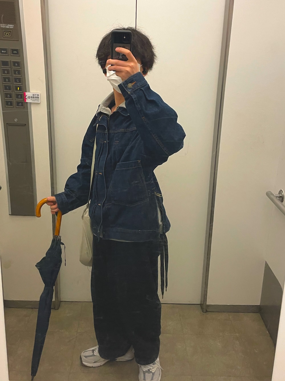 グレー系のスニーカー、ブルー系のデニムパンツ、ベージュ系のショルダーバッグを着用したメンズの春コーディネートの2枚目の写真