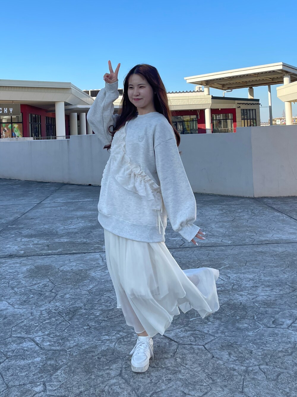 ベージュ系のスウェット、ホワイト系のスカート、ホワイト系のスニーカーを着用したレディースの春コーディネートの4枚目の写真