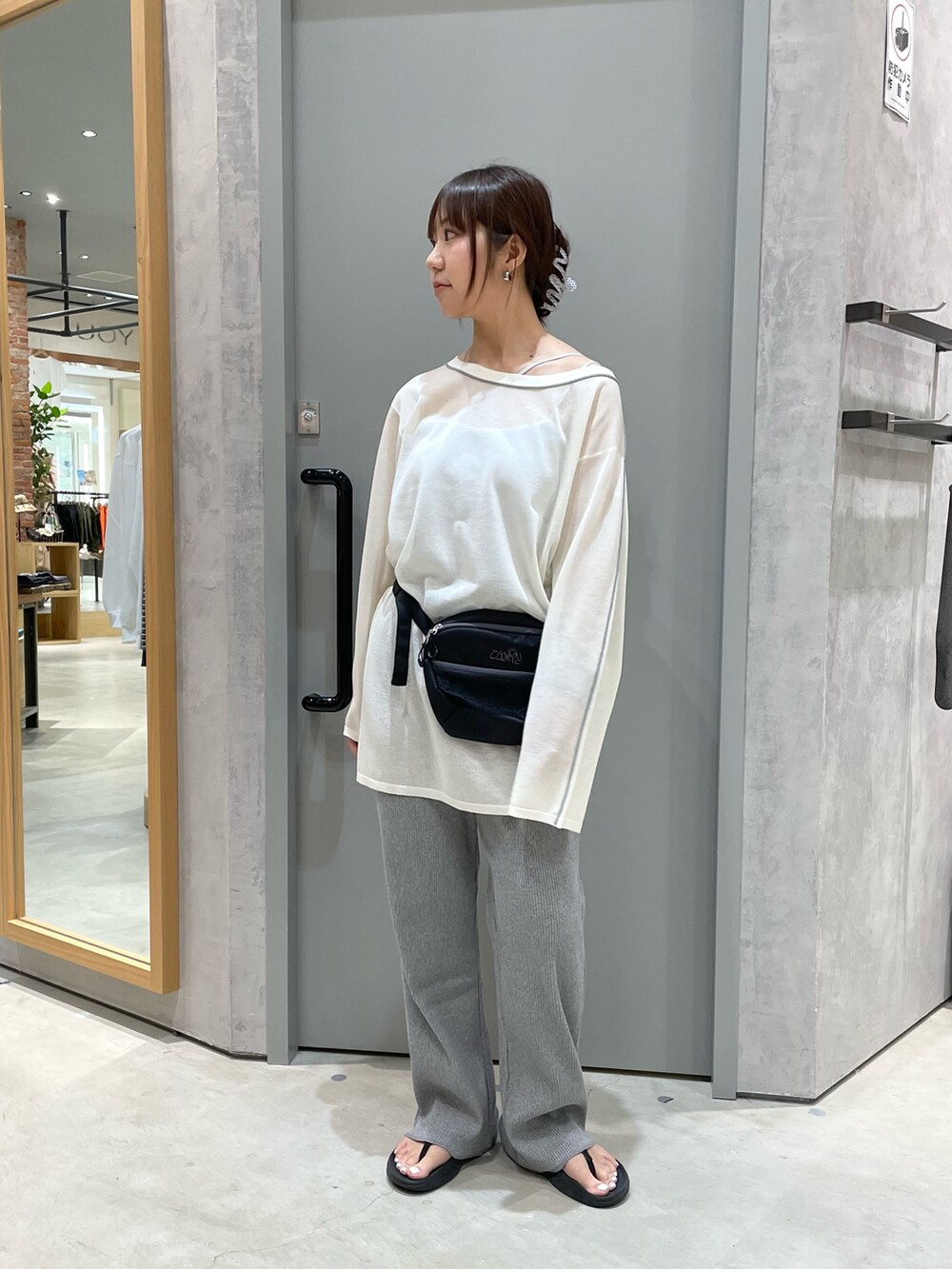 ブラック系のボディバッグ/ウエストポーチ、ホワイト系のニット/セーター、グレー系のその他パンツを着用したレディースの春コーディネートの2枚目の写真