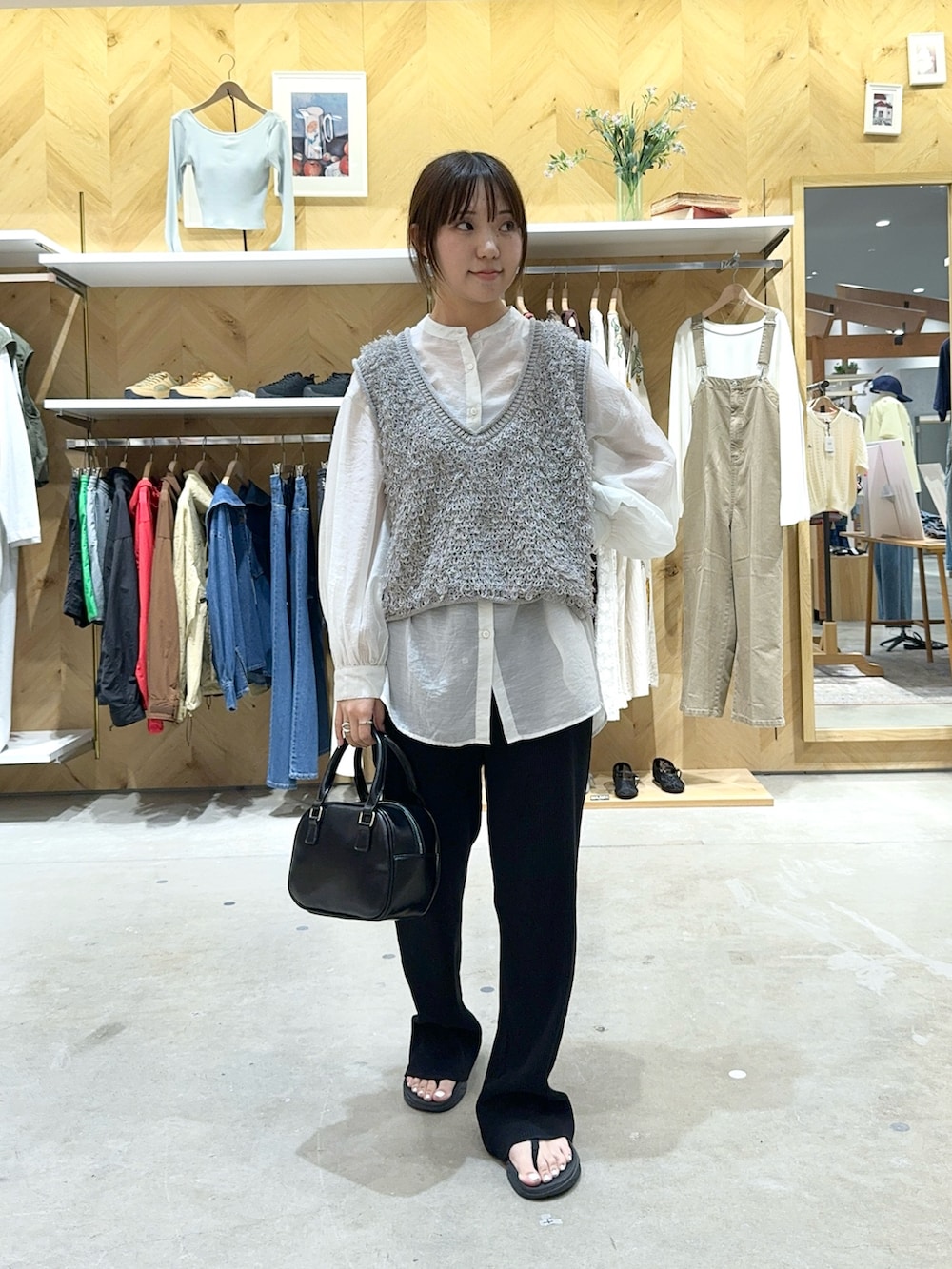 グレー系のベスト、ホワイト系のシャツ/ブラウス、ブラック系のその他パンツを着用したレディースの春コーディネートの2枚目の写真