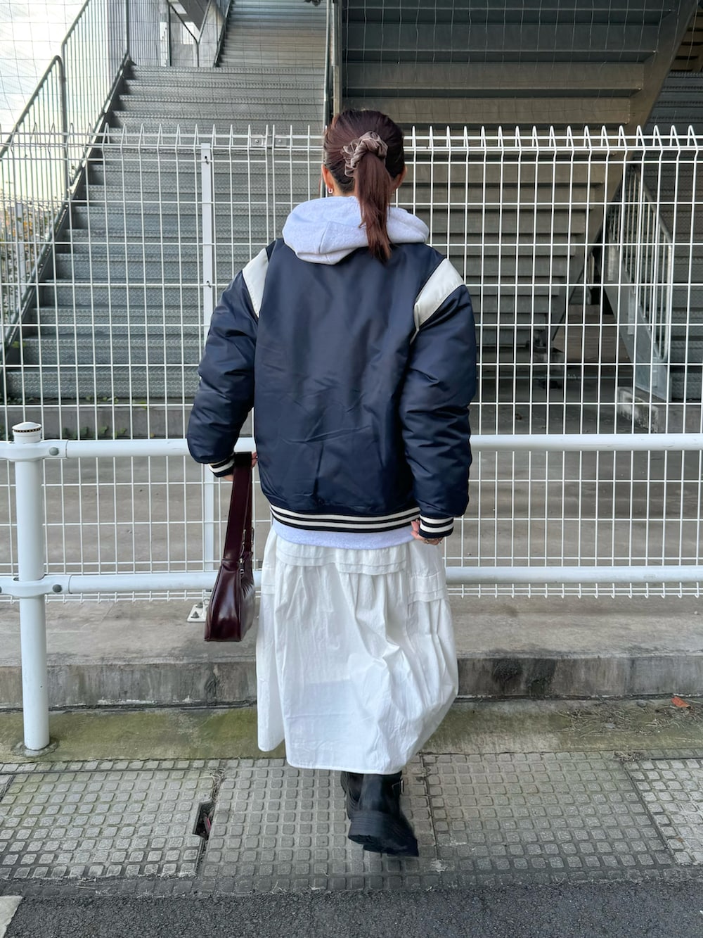 グレー系のパーカー、ブルー系のスタジャン、ホワイト系のワンピースを着用したレディースの冬コーディネートの3枚目の写真