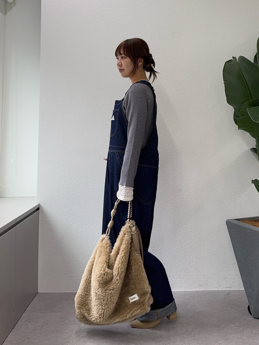ブルー系のサロペット/オーバーオール、ベージュ系のブーツ、グレー系のニット/セーターを着用したレディースの秋コーディネートの3枚目の写真