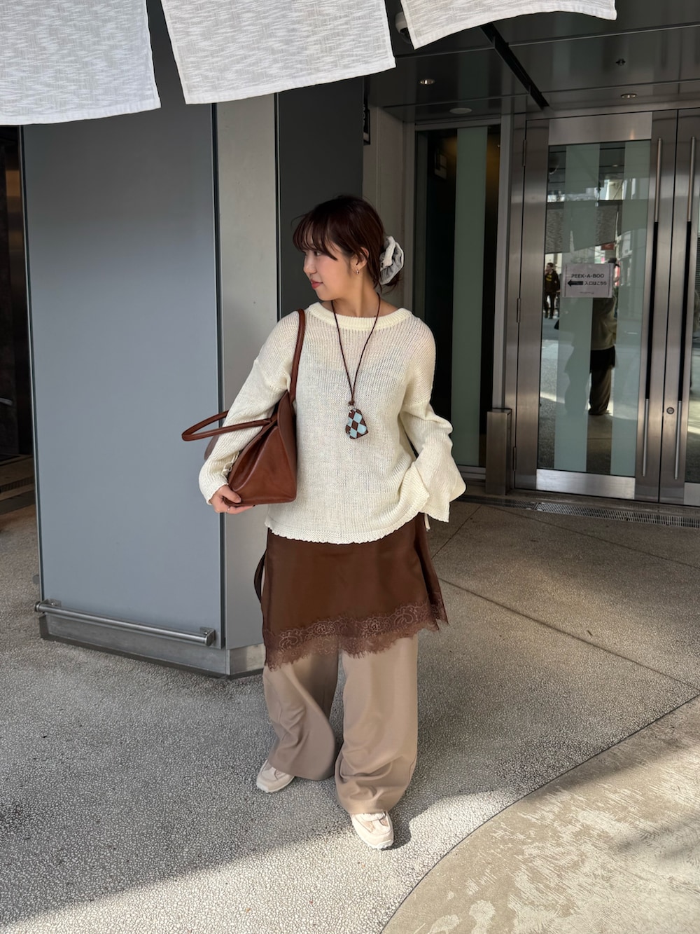ベージュ系のスラックス、ホワイト系のスニーカーを着用したレディースの春コーディネートの2枚目の写真