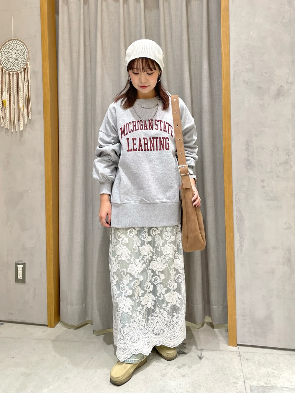 グレー系のスウェット、ブルー系のデニムパンツ、ホワイト系のスカートを着用したレディースの冬コーディネートの2枚目の写真