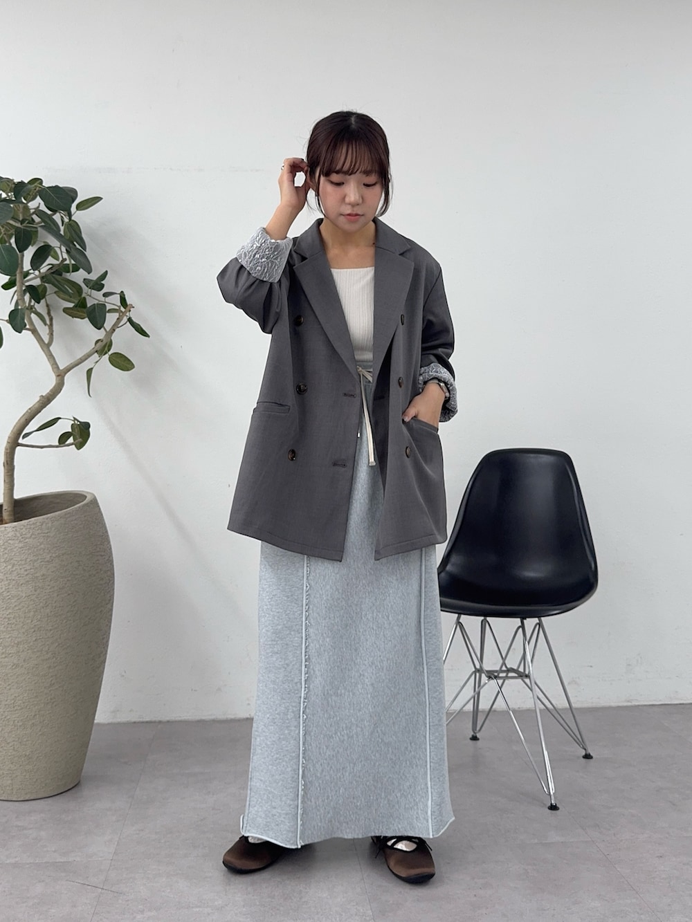 グレー系のテーラードジャケット、グレー系のスカート、ブラウン系のパンプスを着用したレディースの春コーディネートの2枚目の写真