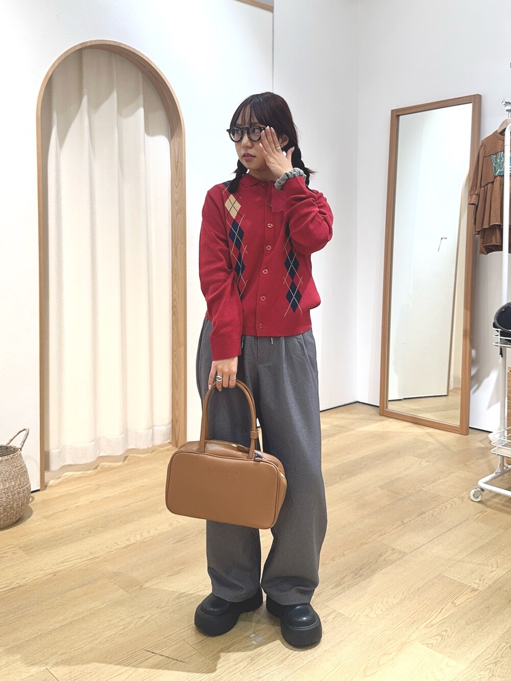 レッド系のカーディガン/ボレロ、グレー系のスラックス、イエロー系のボストンバッグを着用したレディースの秋コーディネートの2枚目の写真