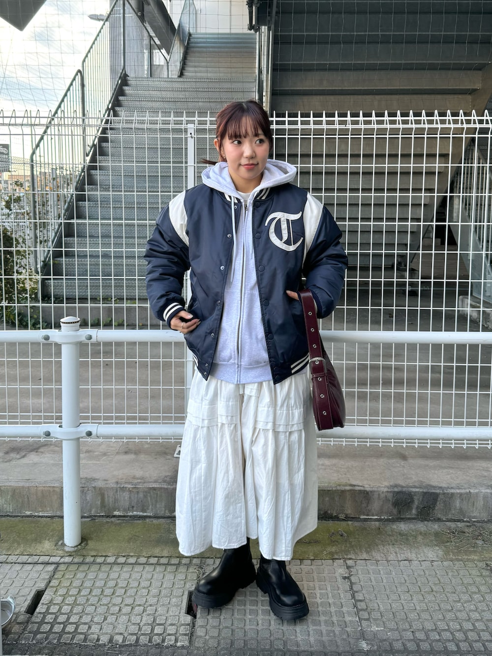 グレー系のパーカー、ブルー系のスタジャン、ホワイト系のワンピースを着用したレディースの冬コーディネートの2枚目の写真