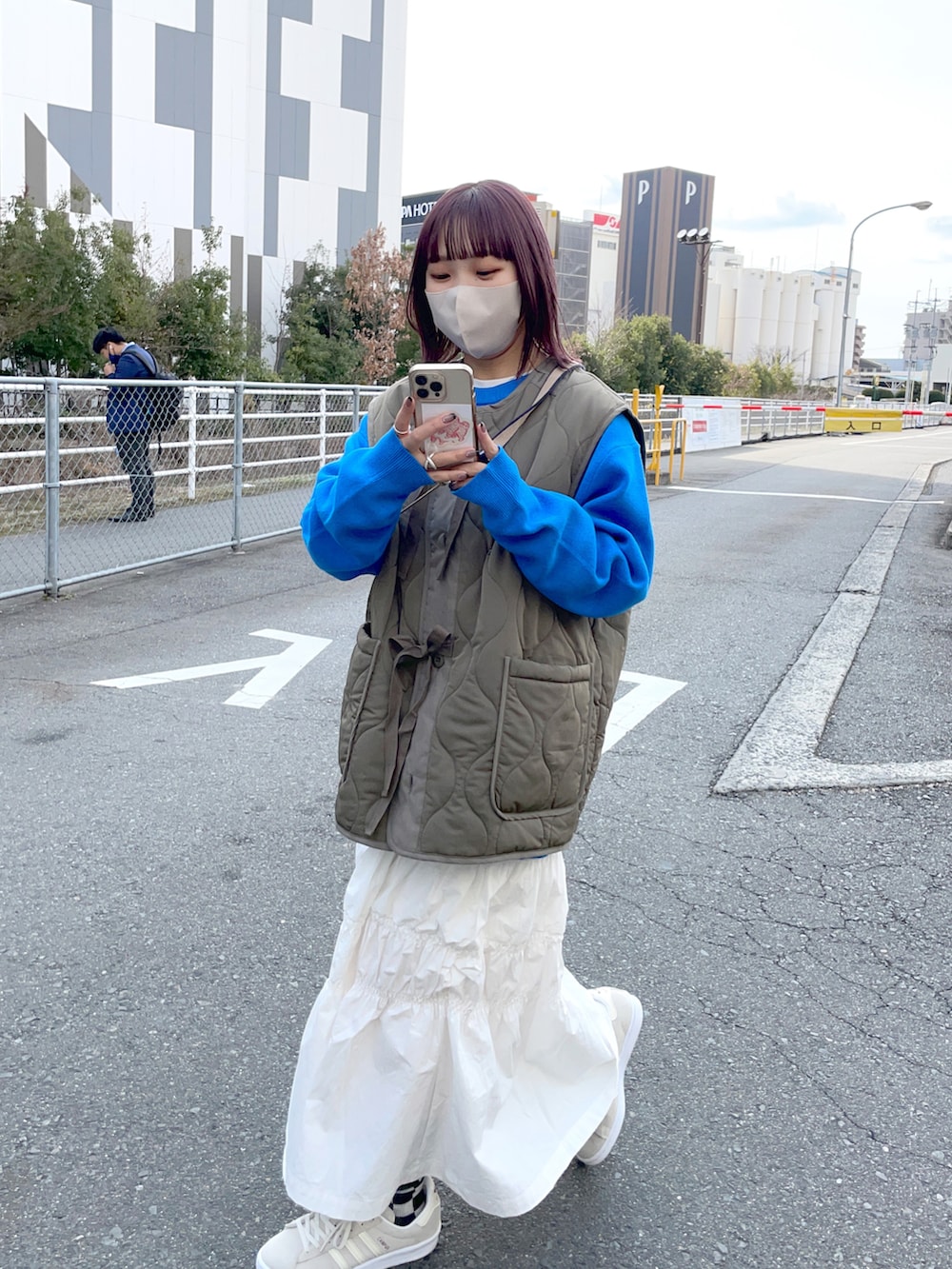 グリーン系のベスト、ホワイト系のスカート、ホワイト系のスニーカーを着用したレディースの冬コーディネートの5枚目の写真