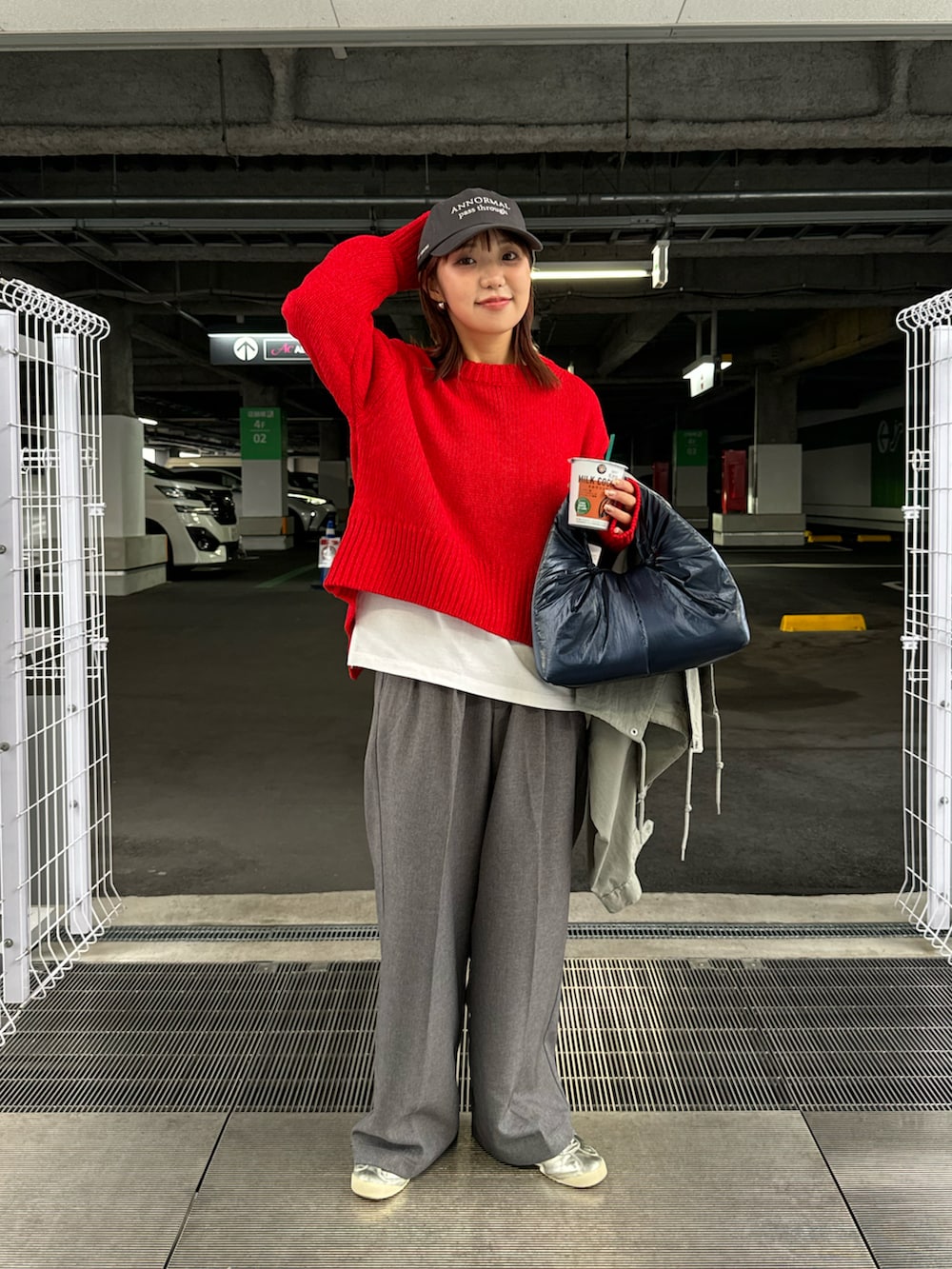 レッド系のニット/セーター、ブルー系のトートバッグ、グレー系のスラックスを着用したレディースの冬コーディネートの2枚目の写真