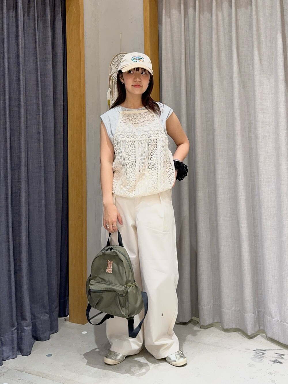グレー系のタンクトップ、ホワイト系のシャツ/ブラウス、グリーン系のバックパック/リュックを着用したレディースの春コーディネートの2枚目の写真