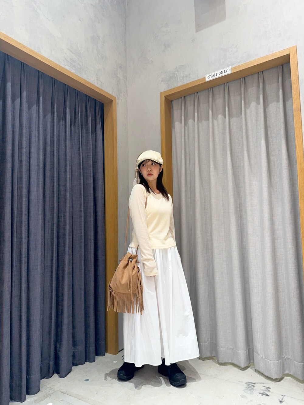 ホワイト系のスカート、ブラウン系のショルダーバッグ、ブラック系のスニーカーを着用したレディースの春コーディネートの3枚目の写真