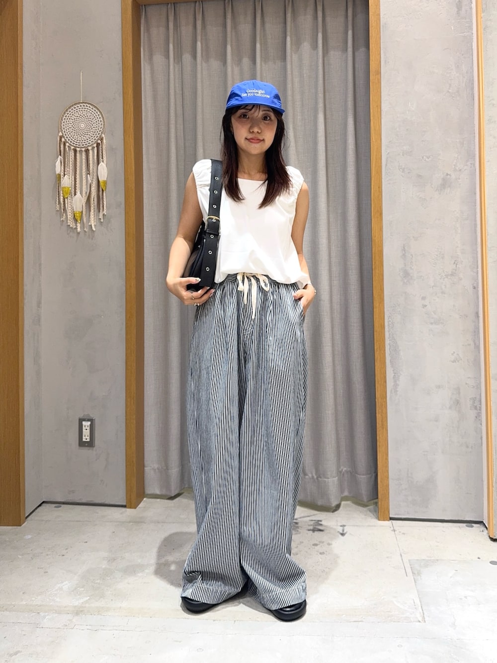 ブルー系のデニムパンツ、ホワイト系のTシャツ/カットソー、ブラック系のトートバッグを着用したレディースの夏コーディネートの2枚目の写真