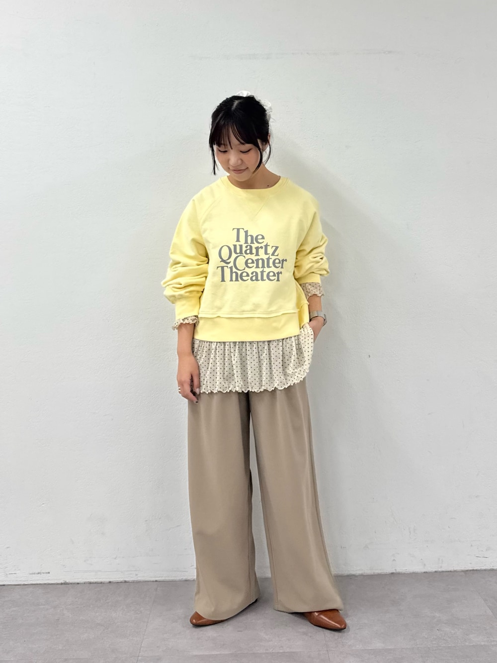 イエロー系のスウェット、ホワイト系のTシャツ/カットソー、ベージュ系のスラックスを着用したレディースの春コーディネートの3枚目の写真