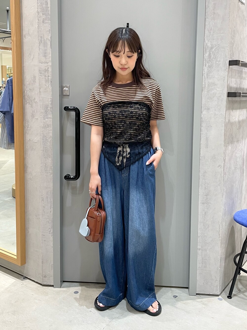 ブルー系のデニムパンツ、ブラウン系のTシャツ/カットソー、ブラウン系のトートバッグを着用したレディースの夏コーディネートの2枚目の写真