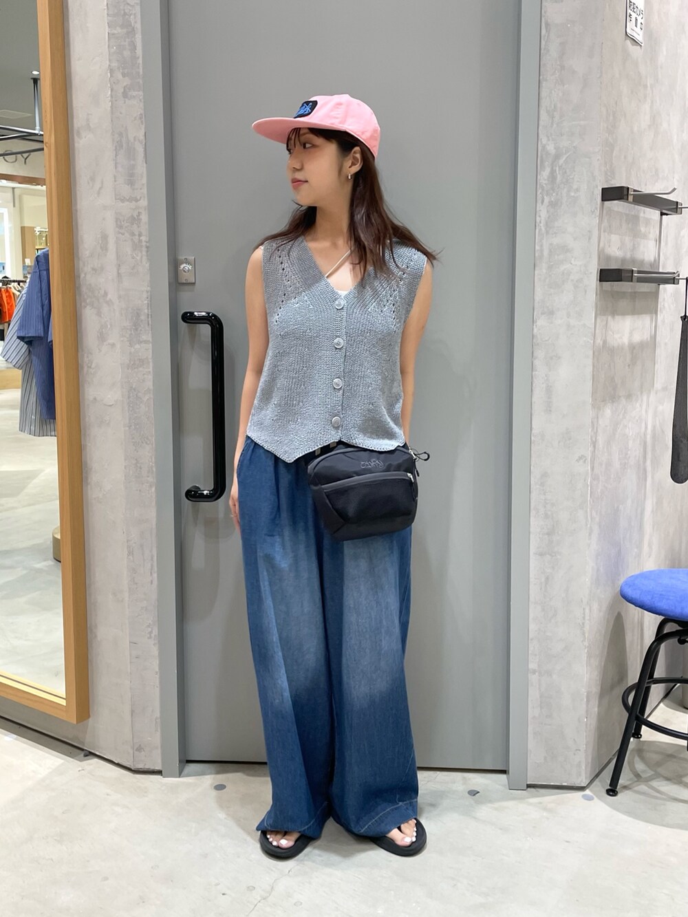 グレー系のベスト、ブルー系のデニムパンツ、ブラック系のボディバッグ/ウエストポーチを着用したレディースの夏コーディネートの2枚目の写真