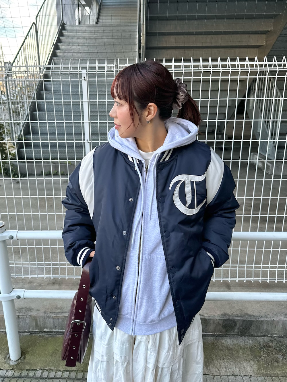 グレー系のパーカー、ブルー系のスタジャン、ホワイト系のワンピースを着用したレディースの冬コーディネートの4枚目の写真