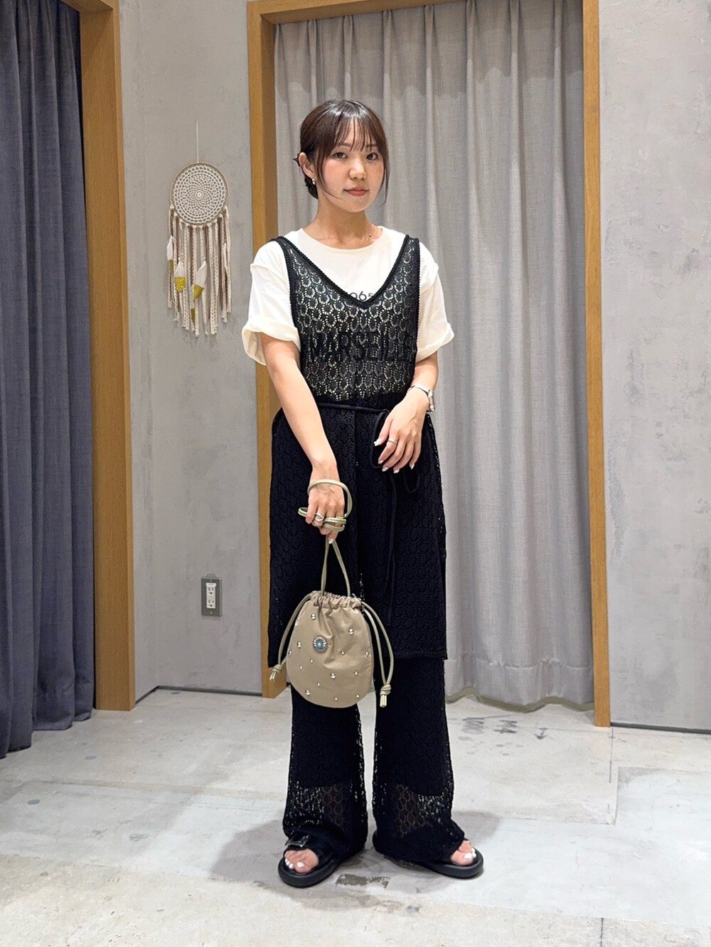 ブラック系のニット/セーター、ブラック系のその他パンツ、グリーン系のハンドバッグを着用したレディースの夏コーディネートの2枚目の写真