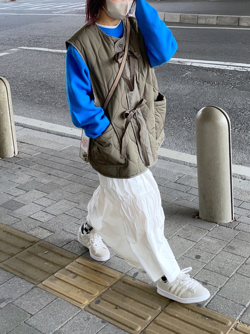 グリーン系のベスト、ホワイト系のスカート、ホワイト系のスニーカーを着用したレディースの冬コーディネートの3枚目の写真