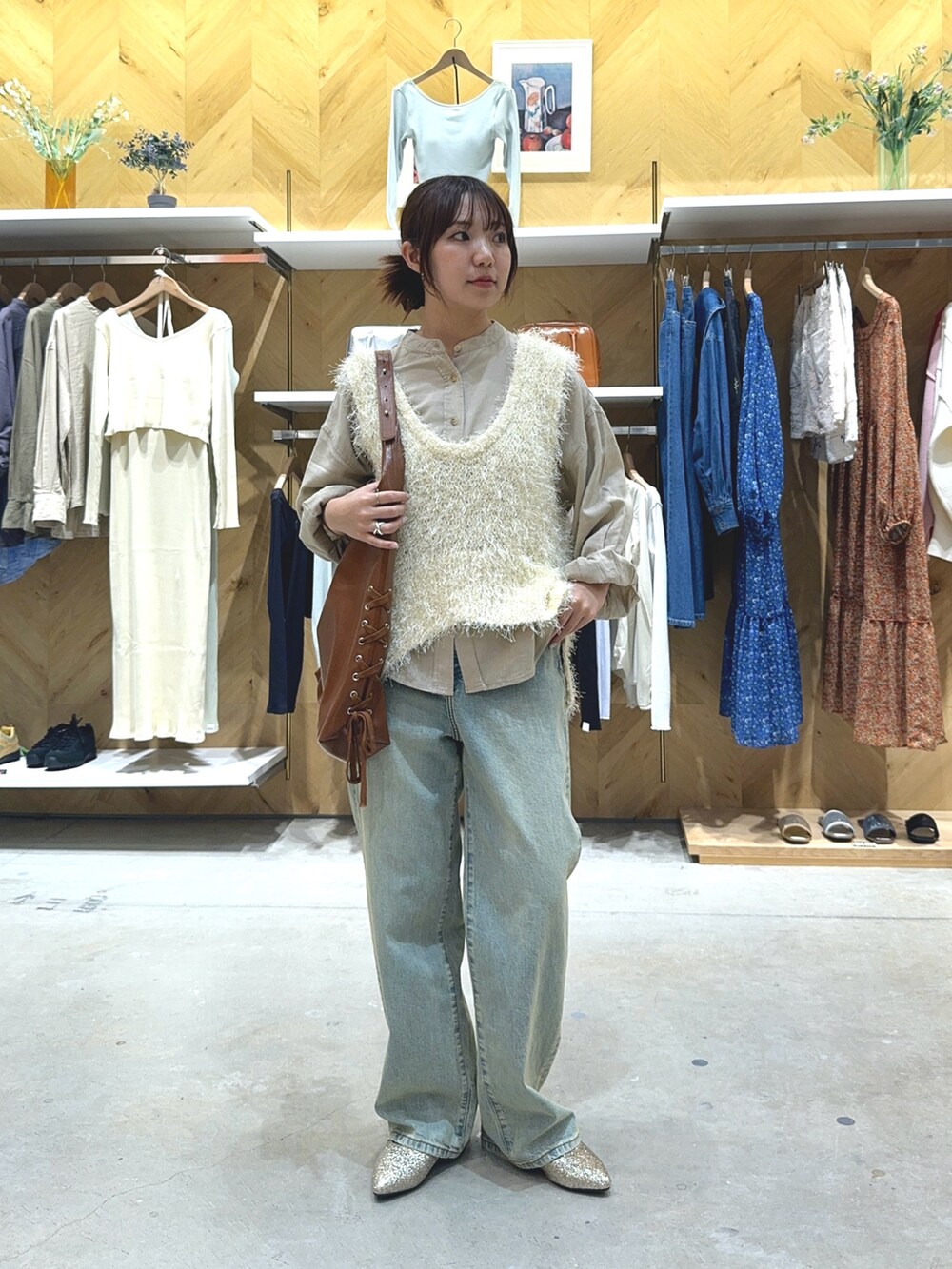 ホワイト系のベスト、ベージュ系のシャツ/ブラウス、ブルー系のデニムパンツを着用したレディースの春コーディネートの2枚目の写真