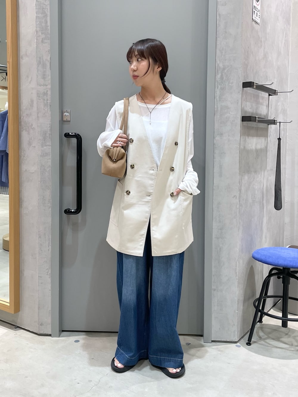 ベージュ系のベスト、ホワイト系のTシャツ/カットソー、ブルー系のデニムパンツを着用したレディースの夏コーディネートの2枚目の写真