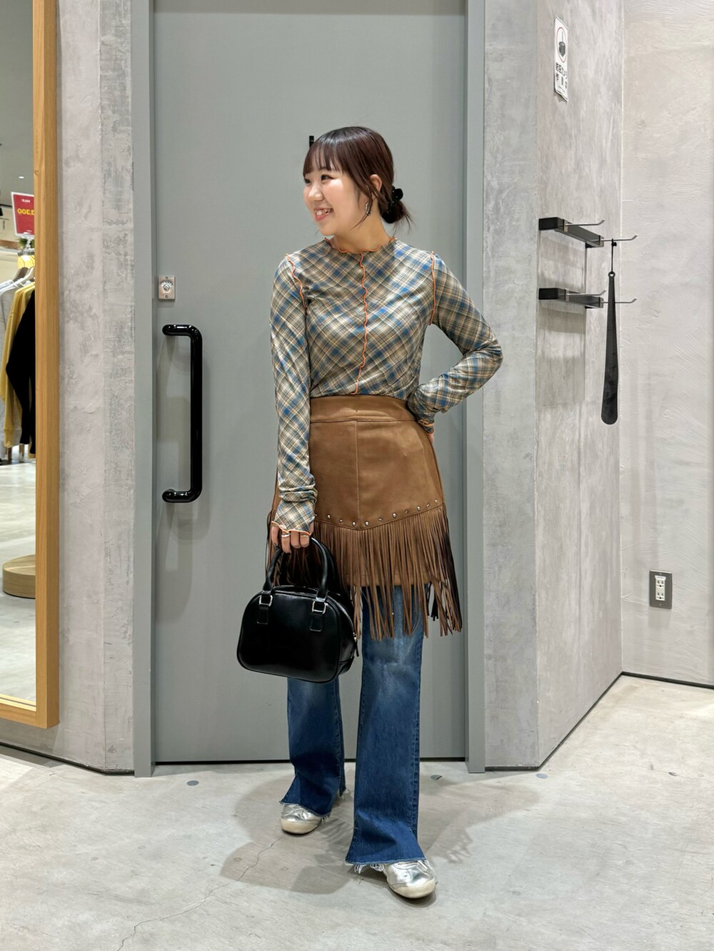 ブルー系のTシャツ/カットソー、ブラウン系のスカート、ブラック系のショルダーバッグを着用したレディースの春コーディネートの2枚目の写真