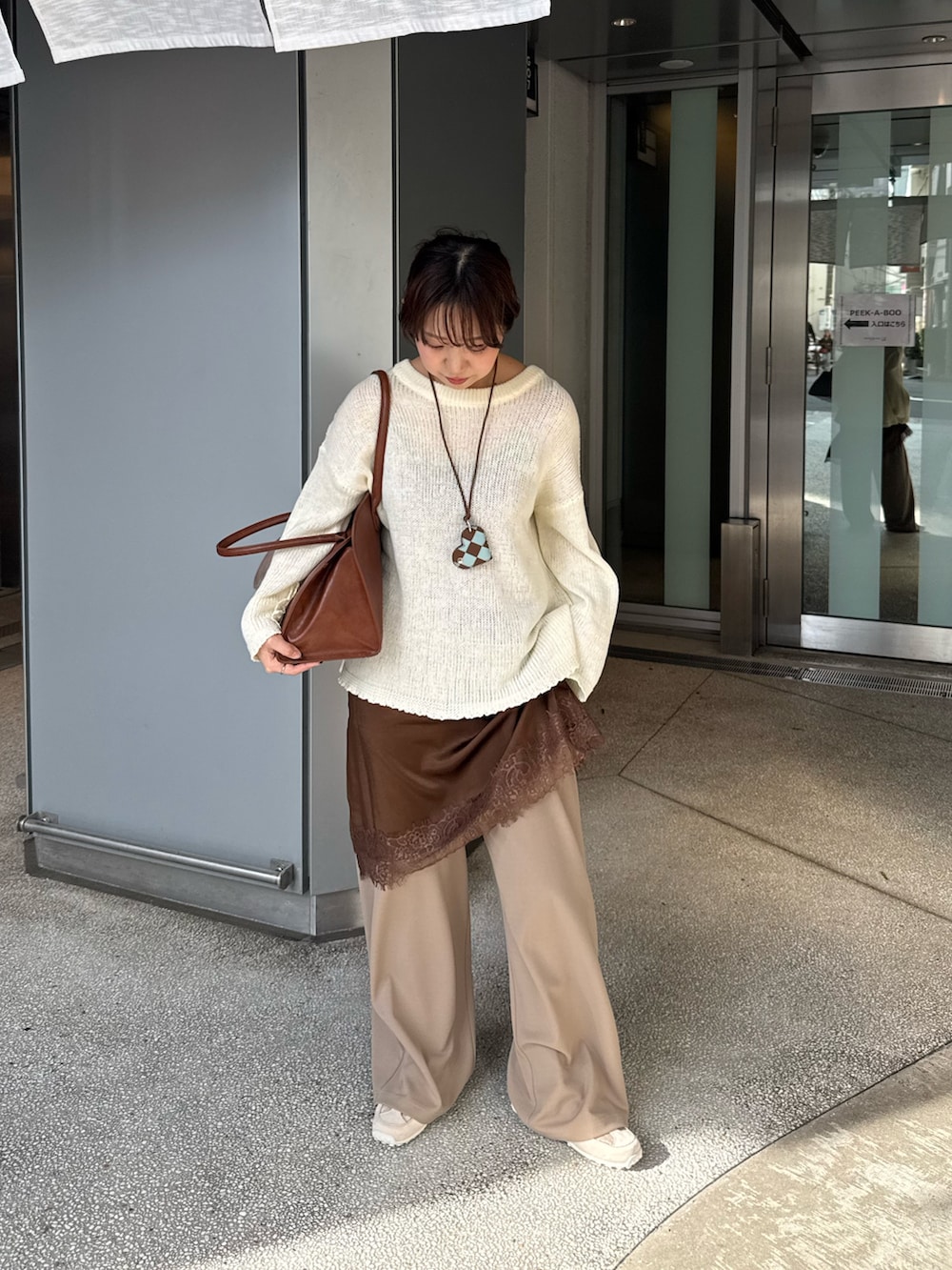 ベージュ系のスラックス、ホワイト系のスニーカーを着用したレディースの春コーディネートの3枚目の写真