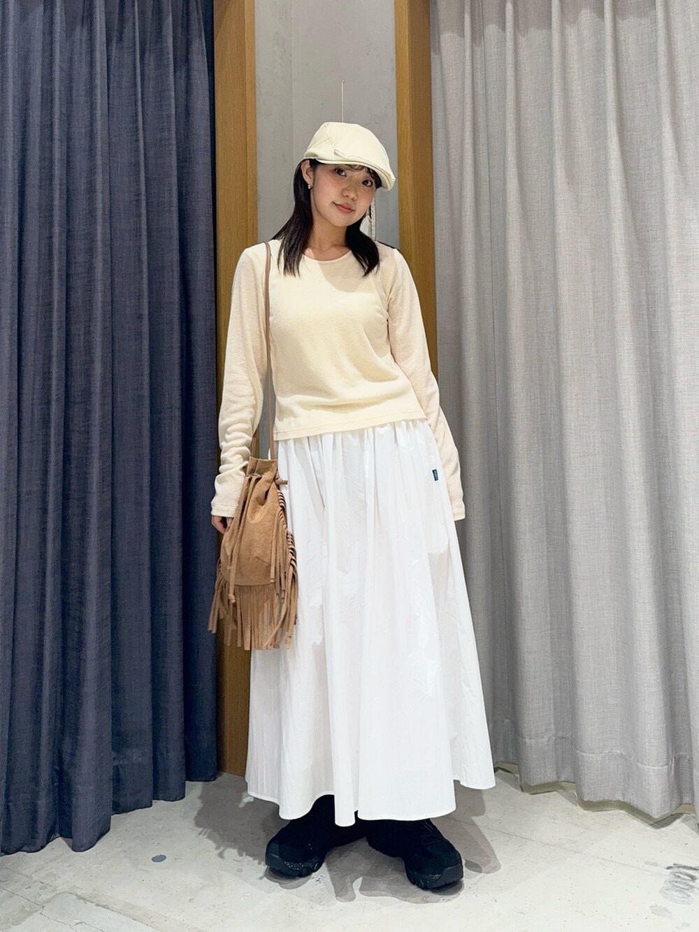 ホワイト系のスカート、ブラウン系のショルダーバッグ、ブラック系のスニーカーを着用したレディースの春コーディネートの2枚目の写真