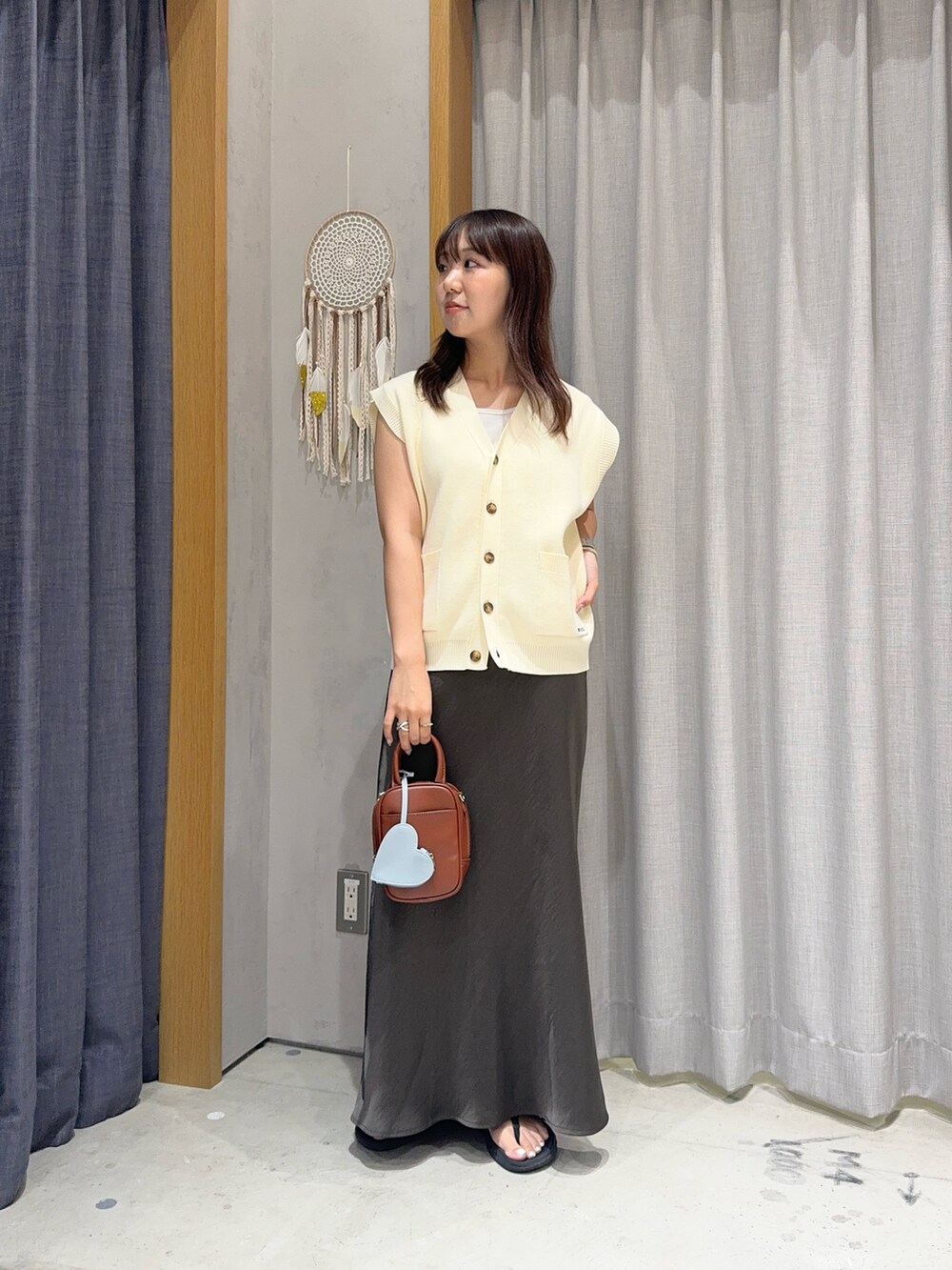 ホワイト系のニット/セーター、グレー系のスカート、ブラウン系のトートバッグを着用したレディースの夏コーディネートの2枚目の写真