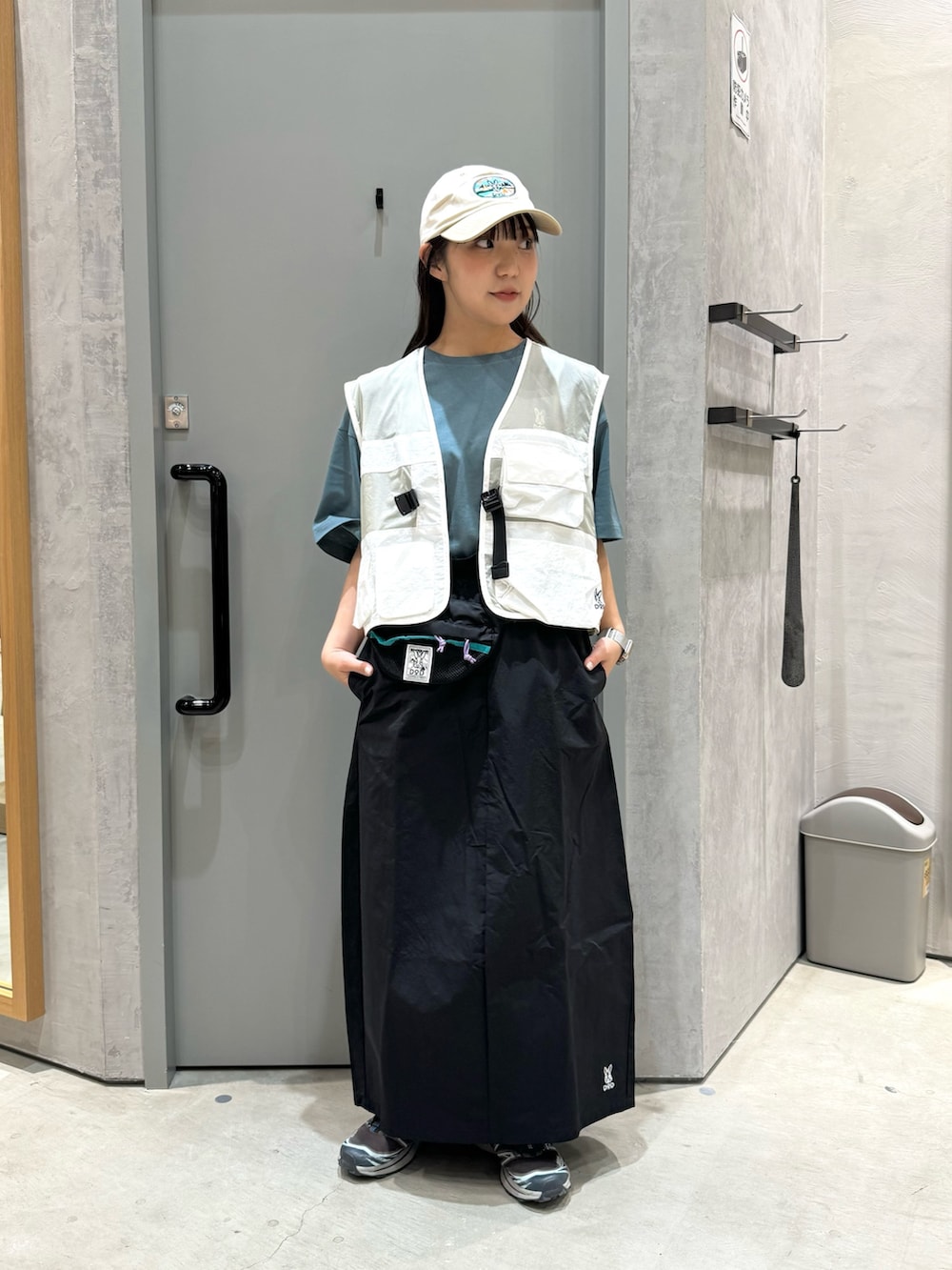 ブラック系のスカート、ホワイト系のベスト、ブラック系のトートバッグを着用したレディースの春コーディネートの2枚目の写真